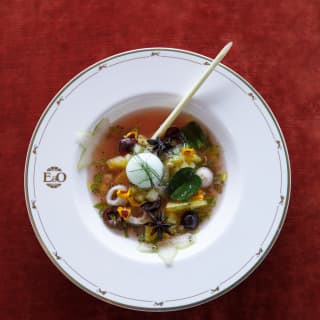 Chef Andre Chian's “nine peppers jus” herby sixteen-hour-braised beef cheek, served in a white bowl on a red tablecloth.​⁣