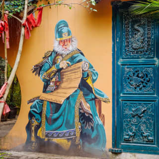 On a yellow courtyard wall, the mural of the Monkey General guards the blue moon gate of George Town's heritage China House.