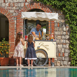 Two little girls ordering ice cream from a poolside gelato stand