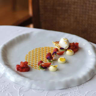 In the crater of a high-sided plate, a parade of strawberry, honey, rosemary and pollen dots creates a refined light dessert.
