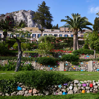 Stone walls edge four tiers of the hotel garden as it climbs the hillside. Odd stones are painted in happy bright colours