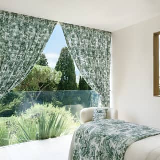 Green floral curtains are pulled back, theatre-style, to reveal lush gardens in the view from the Dior Garden of Dreams spa