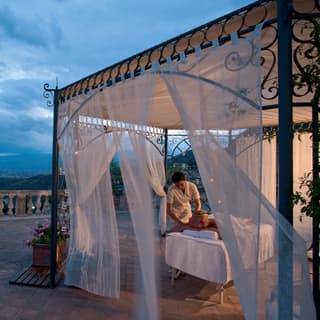 Massage table under an ornate wrought-iron pergola on an Italian villa terrace