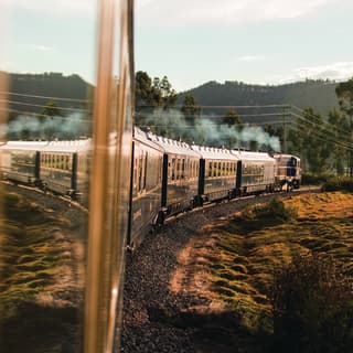 Exterior view of gleaming train carriages curving through a Peruvian valley