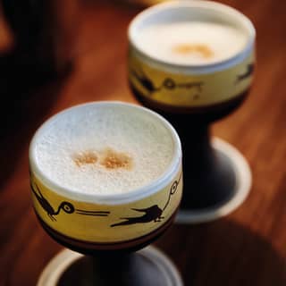 Deux cocktails pisco sour dans des tasses en argile peintes