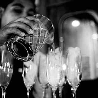 Close up shot of barman's hands pouring a cocktail in glasses