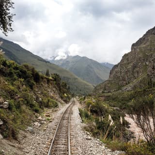 Train tracks stretching into the distance of a valley surrounded by mountains
