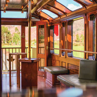 Gleaming wood-panelled train carriage with green leather banquette seating