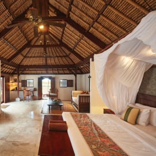 Vast bedroom with a pillowy king-bed under a linen canopy in a double-height villa