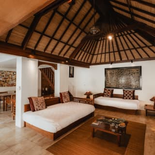 A sofa and day bed with deep white cushions offer total relaxation beneath the cavernous alang-alang roof in the living area.