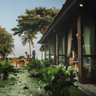 Bifold doors open to immediate views of the lily pond bordering Tunjung restaurant, with the terrace and ocean seen beyond.