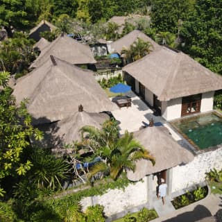 See from above, the thatched rooms of a villa, with a tiled plunge pool and central courtyard, nestle in exotic surrounds.
