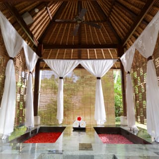 Two sunken baths filled with hibiscus petals in an open-air spa gazebo