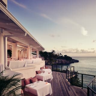 Clifftop restaurant terrace overlooking the Caribbean sea at sunset