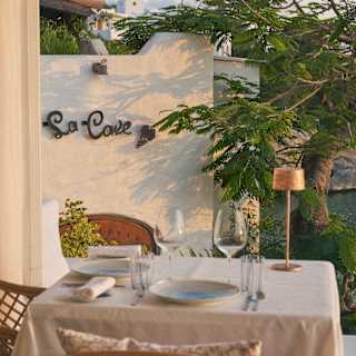 An al-fresco table for two with plates and wineglasses awaits guests at L'Oursin, illuminated by gold evening light.