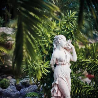 Grecian-style stone statuette among tropical gardens