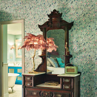 Close-up of an antique vanity table and mirror against blue floral wallpaper