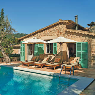 Green shutters join a blue bistro set and turquoise private pool to add colour to the villa's stone walls and terracotta tiles