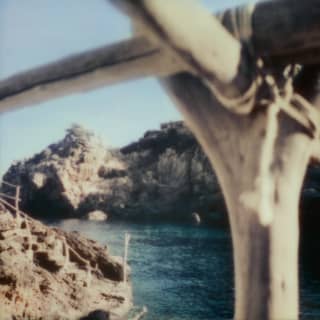 Bleached driftwood is tied together to make railings down to a secret cove where limestone cliffs meet a cobalt dark sea