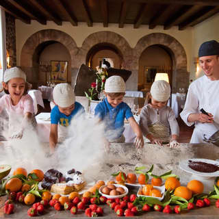 Four kids and a chef standing at a kitchen counter topped with fruit