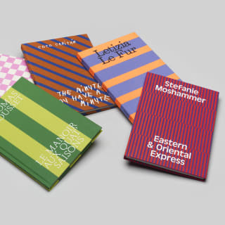 Five books in Belmond's unique 'As Seen By' collection lie scattered on a table-top in bright geometric-pattern covers.