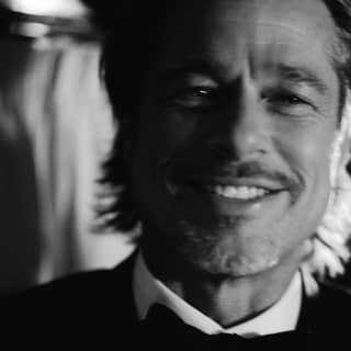 A soft-focus, black and white image of actor, Brad Pitt, smiling in a black bow-tie, white shirt and tuxedo jacket.