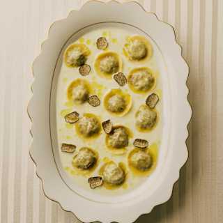 Looking down on a scallop-edged dish of wild boar tortellini served in am unctuous creamy, buttery sauce with truffle shavings.