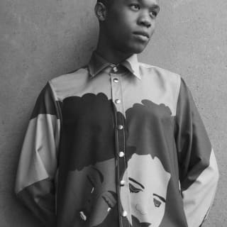 Thebe Magugu, photographed by Jodi Bieber in black and white, wears a high-buttoned garment with his Girl Seeks Girl design.