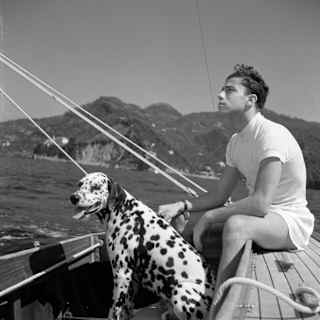 1936 black and white photo of a young man and a Dalmation dog on a sailing boat at sea near Portofino, by Herbert List.