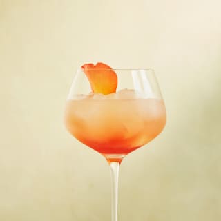 A rose petal garnishes a Portofino Spritz, which looks like sunset in a glass, with lemon juice, gin, rose liqueur and syrup.