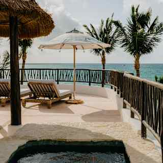 A wood rail surrounds Villa Xuxú's terrace which has a pool, thatched shade and lounge-chairs facing a blissful sea view.