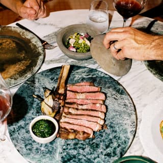 Linz cowboy ribeye grilled over zapote wood and served on a grey marble plate takes centre stage at a dining table at Woodend.