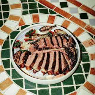 A plate of charred beef slices with grilled fennel and chilis stuffed with chimichurri, seen on an ornate tiled table at Woodend.