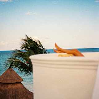 A guest rests her legs on a white roof terrace wall, body obscured by its curve, in a view that captures the blue sea beyond.
