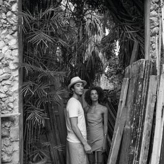 black and white photo of a couple standing under a stone arch with old wooden doors