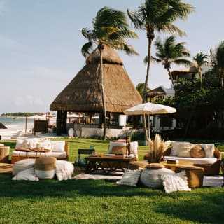 Sofas, wicker chairs and white cushions create a heavenly event space on the lush lawn of Coronas Garden, next to the sea.