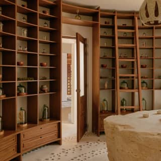 Bottles and jars adorn the full-length wood shelving that wraps round the inside of the Apothecary with a library ladder.