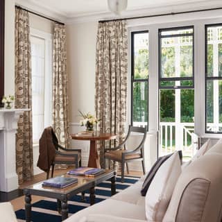 Huge windows pour light into the chic Garden Cottage living room, with a large cream sofa, monotone rug and wooden furniture.