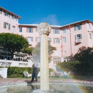 A rainbow dances in spray falling from the top of the ornate stone pillar water feature in Mount Nelson Hotel's fountain.