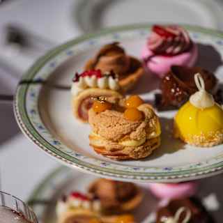 Looking down in close-up on the top tier of a sweet stand with a variety of exquisitely-made cakes, sweets and macarons.