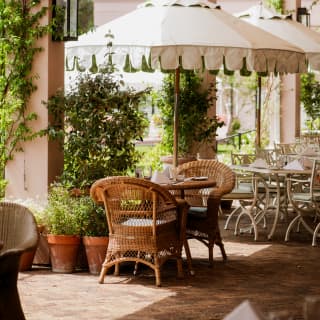 Surrounded by foliage, a wicker table for two enjoys the shade of a parasol beneath the canopy awning on the Oasis terrace.