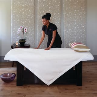 A staff making bed in a spa suite