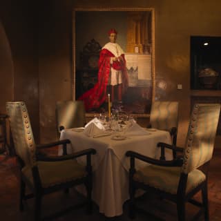 Table for four in a low-lit restaurant with a large portrait of a cardinal behind
