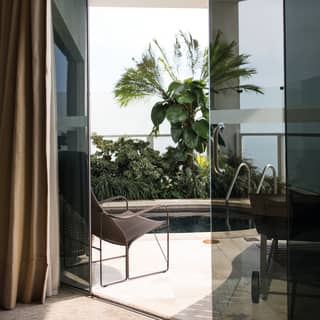 View through glass doors to a plunge pool on a garden-filled balcony
