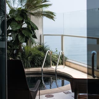 View through glass doors to a balcony plunge pool overlooking the Pacific Ocean