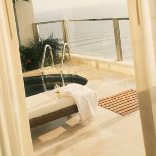 Low-saturation, angled image of the Presidential Pool Suite balcony with bench, luxury plunge pool and expansive sea views.
