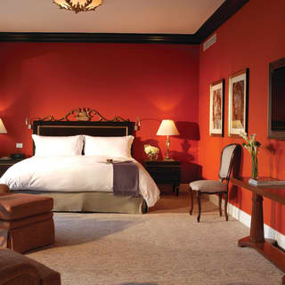 A painted terrace suite bedroom with warm red walls and neutral grey carpet