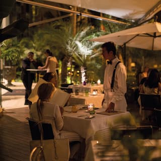 After dark, guests place their dinner orders to a waiter at the candlelit Restaurant Tragaluz