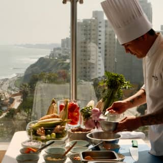 A chef in whites and a toque prepares ingredients at an outside table at The Observatory in preparation for a Ceviche class.