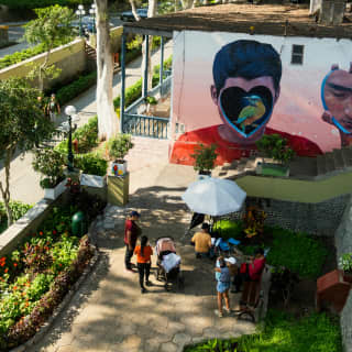 People gather to look at a mural of a bird inside a heart covering a boy's face, seen from above in the district of Barranco.